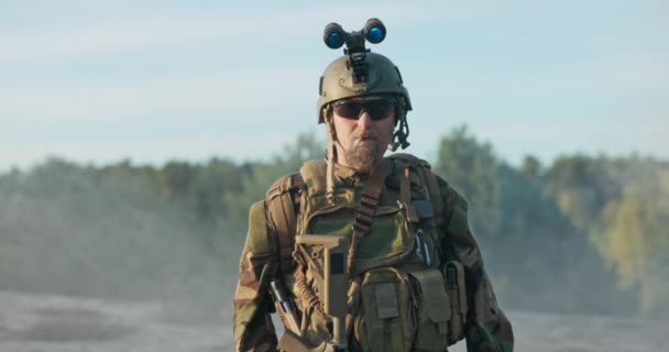 Командир армии отдыхает от службы, стоит в форме и шлеме с сигаретой во рту, охраняя территорию, базу, дурные привычки солдата, не выполняя служебных обязанностей — стоковое видео