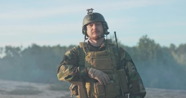 Portrait de soldat vêtu d'uniforme moro casque et ceinture d'équipement homme regarde dans la caméra, prend arme dans les mains et étreint poitrine ayant les bras croisés accomplissement du devoir de défense du pays — Video