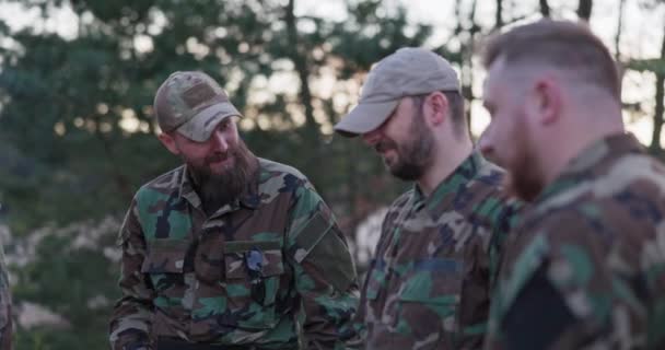 Gesprek van soldaten in camouflage kleding, bespreken ze in de avond door de gemeenschappelijke kampvuur bakken worsten voor het avondeten, mannen rusten na het werk, dienst, veldoefeningen — Stockvideo