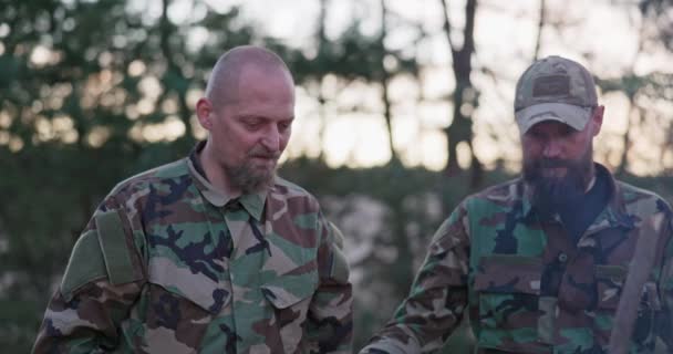 Conversación de soldados en ropa de camuflaje, que están discutiendo en la noche por la hoguera común freír salchichas para la cena, los hombres están descansando después del trabajo, servicio, ejercicios de campo — Vídeo de stock