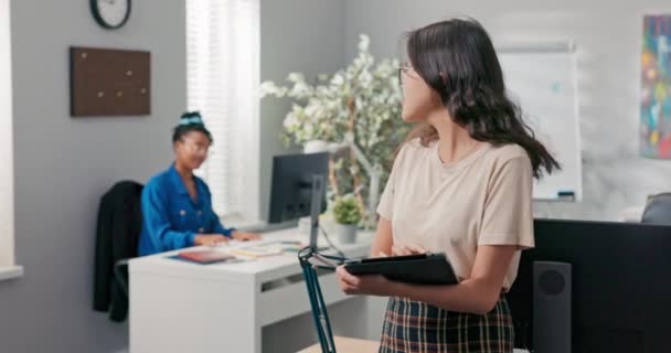 De marketing manager, een mooi meisje met een bril, houdt een tablet in haar hand, controleert het bereik op social media, bespreekt met een collega van het bedrijf over resultaten, vooruitgang — Stockvideo