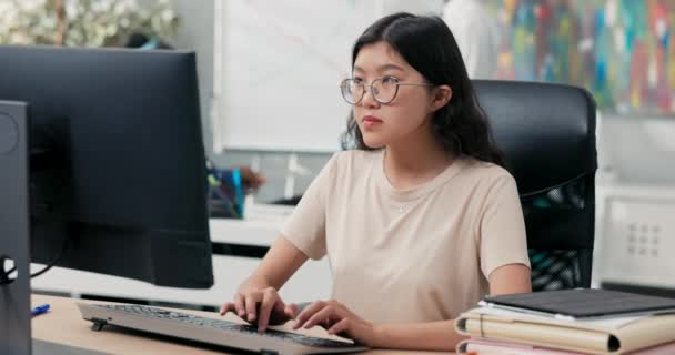 大きなメガネとtシャツのオタクの女の子は、机の前に快適な椅子に座って、コンピュータのキーボードで指をタップし、メッセージを送信し、電子メールを送信し、バック書き込み、会社のウェブサイト、オフィスライフ、企業を実行します — ストック動画