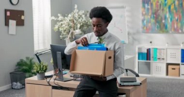 Saçları afro saçlı bir adam şirketten ayrılıp, kutuya doldurulmuş eşyalarla ofisten çıkıyor. Şirketin sorumluluklarını bırakıyor. Sosyal odayı terk ediyor.