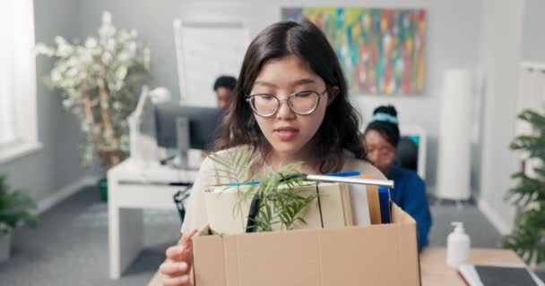 Vrouw gekleed in slimme kleren, bril, ambitieuze werknemer verlaat kantoor, verandert van positie, verhuist naar een ander bureau, draagt accessoires verpakt in kartonnen doos, afscheid, glimlach, tevredenheid — Stockvideo