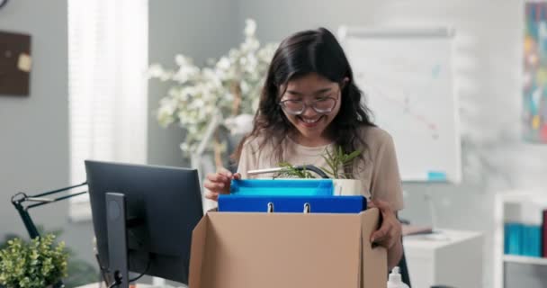 Hermosa mujer con belleza asiática coreana obtiene un ascenso en la oficina, cambia de posición, lleva sus cosas empaquetadas en una caja, las mueve, deja el trabajo, ella es feliz sonriendo, deja la compañía — Vídeo de stock