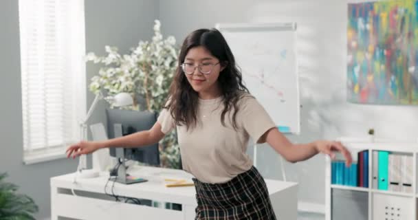 Heureuse travailleuse de bureau satisfaite a obtenu une promotion elle danse entre bureaux en compagnie, femme à la beauté coréenne est gaie, souriante, dans une pause de ses fonctions elle pratique une nouvelle chorégraphie — Video