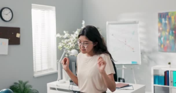 A beautiful woman dances in an office, a company, a corporation between the desks of co-workers, she is happy, smiling joyful, she finishes her job early, gets a promotion, changes position — Stock Video