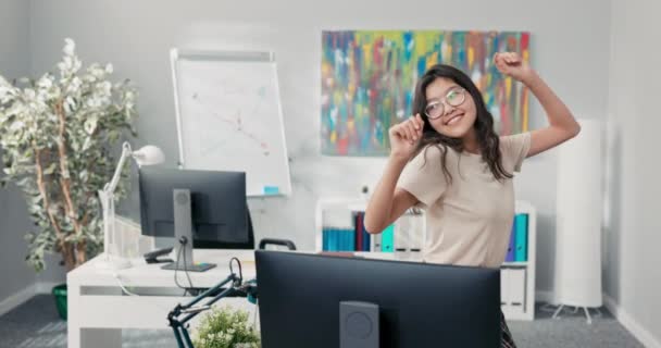 幸せなサラリーマンは会社の机の間で踊り、韓国の美を持つ女性は陽気で笑顔で、仕事を休んで新しい振付を練習する。 — ストック動画