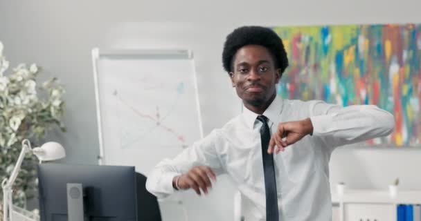 Hombre con bailes afro en medio de la oficina de la compañía, practicando nuevos movimientos antes del evento, feliz de ganar un contrato, buenas noticias, empleado consiguió un ascenso, termina el trabajo antes, paga más alta — Vídeos de Stock