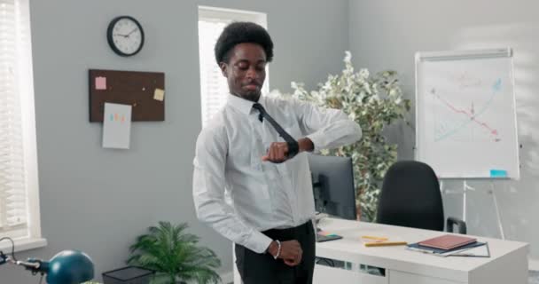 Man met afro gekleed in wit shirt en stropdas dansen in het midden van het kantoor in het bedrijf, oefenen van nieuwe moves voor het evenement, blij om de tender te winnen, goed nieuws, gelukkige werknemer kreeg promotie — Stockvideo