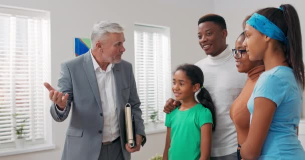 Expérimenté agent immobilier mature montre la famille autour de l'appartement à vendre points de location — Video