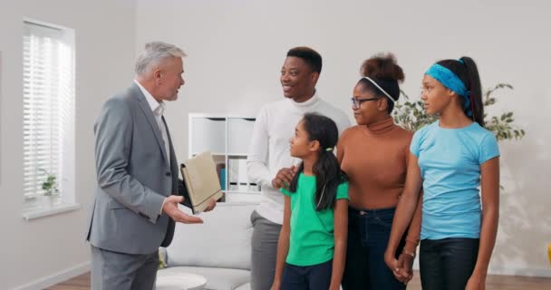 Familjen bestämmer sig för att hyra en lägenhet, de träffar en erfaren fastighetsmäklare, en man med grått hår skakar hand i grattis, tack — Stockvideo