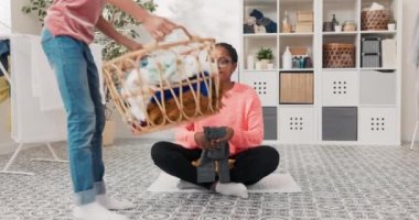 Gözlüklü, gülümseyen bir kadın çamaşır odasında yerde oturur. Kız hasır sepetini banyoda ayırmak için getirir. Küçük kız annesinin etrafında oynar, zıplar.