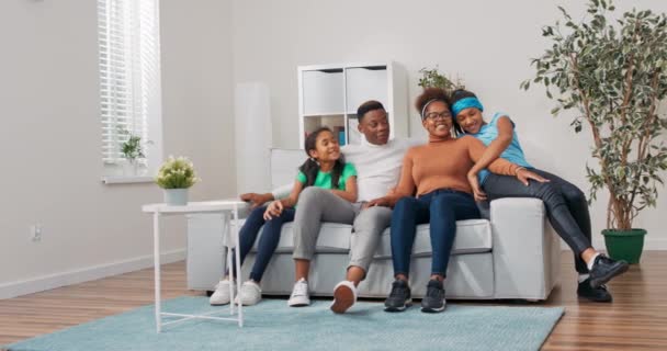 Семейное время, проведенное дома на диване супружеской пары с двумя дочерьми расслабляются на диване, разговаривают, сплетничают, высказывания мнения, обсуждая будущие планы, информируя детей о намерениях — стоковое видео