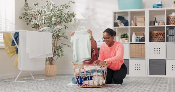 Mère et fille passent du temps ensemble dans la buanderie tout en triant les vêtements colorés préparés pour le lavage, en arrière-plan peignoirs, salle de bains, liquides de lavage, sèche-linge — Video