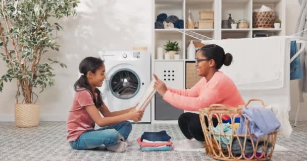 Matka i córka siedzą na podłodze w pralni domu, dziewczyna pomaga kobiecie w pracach domowych, organizują czyste pranie ubrania wyciągnięte z dużego wiklinowego koszyka przybijają piątkę — Wideo stockowe