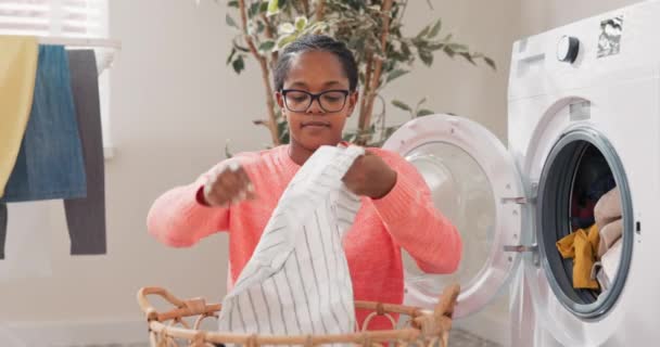 Woman in glasses performs household chores in bathroom, laundry room, kneels with wicker basket filled with clothes at washing machine, loads colorful things into drum, spinning, rinsing — Stock Video
