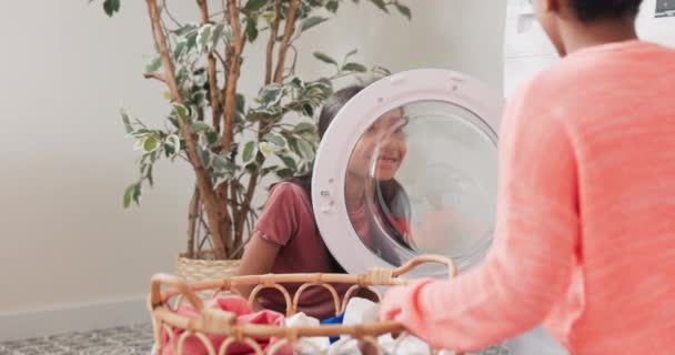 Fooling around, joking, playing while doing household chores, woman and girl hanging out in laundry room, bathroom, showing silly faces to each other through washing machine door — Stock Video