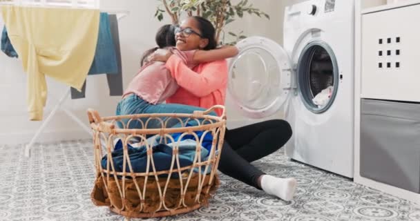 Wanita ceria menghabiskan waktu bersama dengan putri saat melakukan pekerjaan rumah tangga, mereka memilah-milah cucian bersama-sama, membuang barang-barang berwarna-warni ke mesin cuci Gadis kecil memeluk ibu yang berterima kasih atas bantuannya — Stok Video