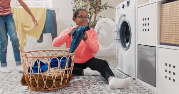 Az örömteli nő együtt tölti az idejét a lányával, miközben házimunkát végez, összepakolják a szennyest, színes tárgyakat dobálnak a mosógépbe, a kislány megöleli az anyját, aki megköszöni neki a segítséget. — Stock videók