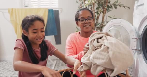 Familj hjälp med hushållssysslor, sätta tvätt i tvättmaskinen, färgglada smutsiga saker tas ur korgkorgen av flickan ges till mamman — Stockvideo