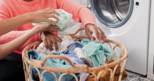 Zbliżenie kobiecych rąk siedzących na podłodze w pralni, sortowanie ubrań, które są w wiklinowym koszu, wrzucanie rzeczy do bębna pralki, prace domowe — Wideo stockowe