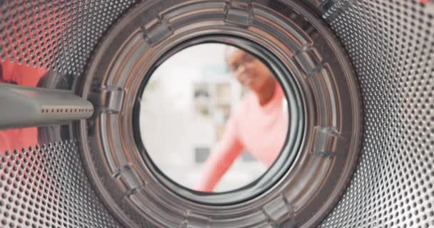 Skjuten inifrån tvättmaskin trumma, kvinna öppnar dörren och förpackningar färgglada kläder inuti, sätter t-shirts, jeans i tvätt — Stockvideo