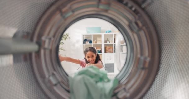 Ein Blick aus dem Inneren der Trommel eines niedlichen kleinen Mädchens, das Spaß dabei hat, bei der Hausarbeit zu helfen, Kleidungsstücke in die Waschmaschine zu werfen und zu zielen, glücklich, Erfolg zu haben. — Stockvideo