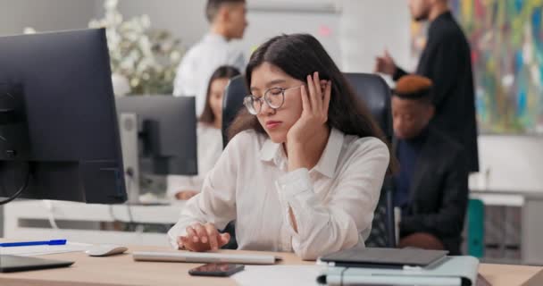 Uttråkad söt kontorssekreterare anställd i en vit skjorta sitter framför datorskärmen, hon är trött, vill sova, stöder hennes ansikte med handen, väntar på slutet av arbetet — Stockvideo
