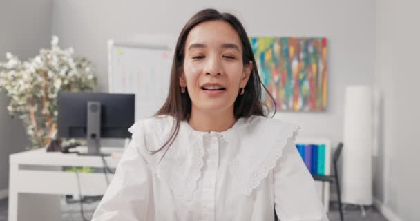 Μια ώριμη όμορφη γυναίκα με λευκό πουκάμισο που εργάζεται σε ένα γραφείο έχει ένα βίντεο διάλειμμα κουβεντιάζοντας με έναν συνάδελφο μέσω υπολογιστή, χαιρετώντας το χέρι σε κάμερα, ακούγοντας τους φίλους της φρικτή ιστορία — Αρχείο Βίντεο