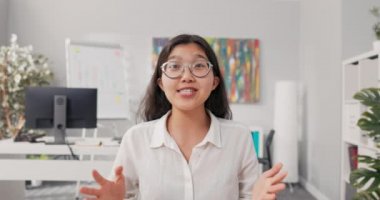 Güzel, gülümseyen, gözlüklü bir Koreli kadın ofiste beyaz gömlek giyerek oturuyor. İş kadını bir video görüşmesi yapıyor, konferanslar yapıyor ve patronuna internetten sorular soruyor.