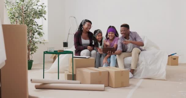 Video call tablet pareja casada y sus hijos llaman a la familia a través de Internet para mostrar apartamento renovado todo el mundo saluda con sonrisa hombre gira con dispositivo mujer explica el progreso — Vídeos de Stock