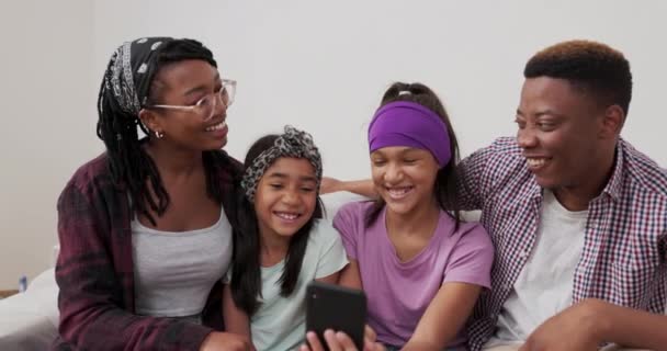 Milovat navzájem šťastný šťastný rodina tráví čas v zrekonstruovaném bytě, které se dívají na fotografie na telefonu legrační obrázky vtipkování komentovat smích — Stock video