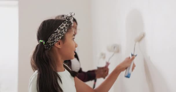 Mãe passa tempo com sua filha juntos eles pintam paredes em um apartamento renovado aplicando tinta branca com rolos brincando — Vídeo de Stock