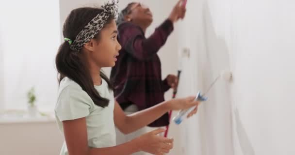 Занятая мама проводит время с веселой дочерью привлекает ее, чтобы помочь вместе они красят стены квартиры в ремонте применить белую краску с роликами — стоковое видео