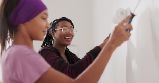 Cute pretty girl paints wall with roller that is covered with white paint together with her mom woman cheers her daughter during renovation high-five — Stock Video