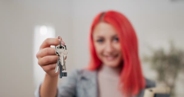 Shot of apartment keys extended on hand toward camera, pink-haired woman dressed in suit holds documents and hands over keys, real estate agent, flat owner, receiving room for use — Stock Video
