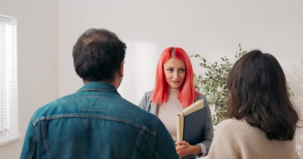 Couple make appointment to see real estate agent pink-haired elegantly dressed owner invites them to look at newly renovated apartment in city center young people think about renting buying first flat — Stock Video