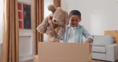 Yeni bir daireye taşındıktan sonra gülümseyen tatlı bir çocuk oyuncaklarının kutuları arasında bir oyuncak ayı bulur ve neşe içinde onu fırlatır.