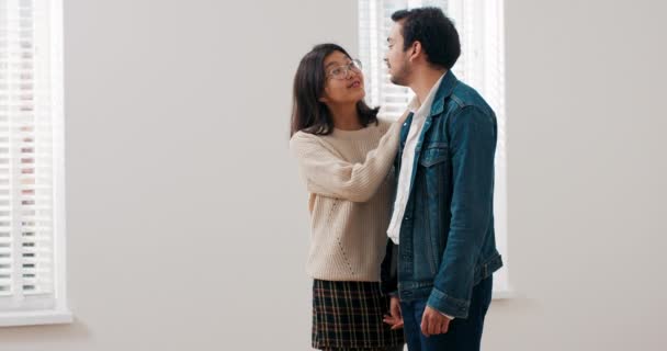 Mladý manželský pár stojí v prázdném koupeném bytě, objímají se, užívají si stěhování, smějí se, jsou šťastní, mluví — Stock video