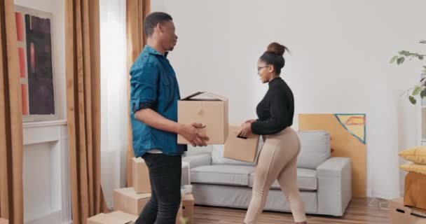 Para zakochanych przynosi ostatnie kartonowe pudełka z przeprowadzki ustawia je na podłodze raduje się, rozgląda się po nowym mieszkaniu, przybija sobie piątki. — Wideo stockowe
