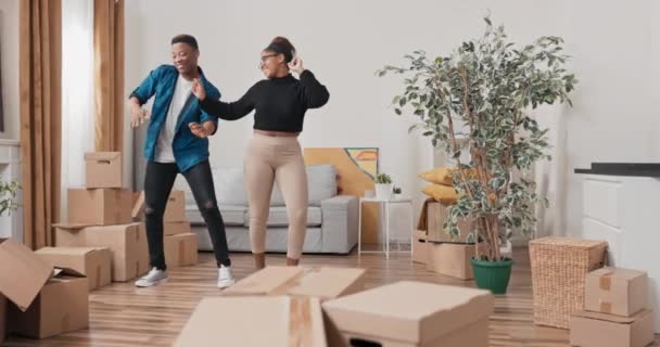 Egy szerelmes pár beköltözik egy új lakásba a kartondobozok eltávolítása egy új fejezet az életben egy ház bérlése a fiú és a lány táncol örömmel — Stock videók
