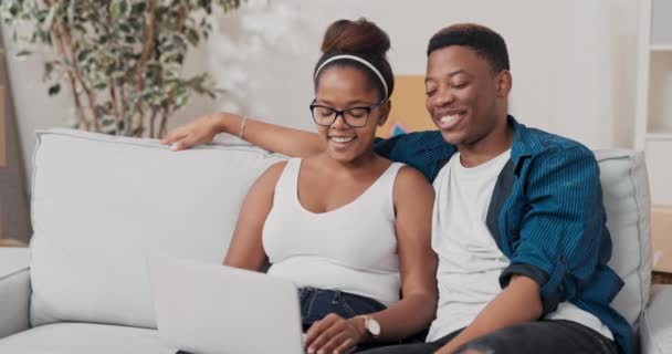 Ζευγάρι ερωτευμένο κάθεται στον καναπέ στο διαμέρισμα μετά τη μετακίνηση μιλώντας με τους φίλους τους γονείς μέσω της κάμερας laptop χαιρετώντας χέρι τέλος σύνδεσης στο internet close computer — Αρχείο Βίντεο