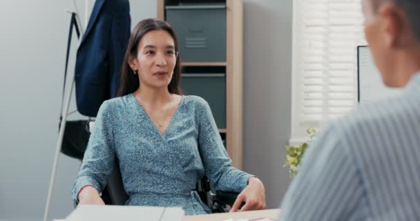 Beautiful pretty Korean Asian woman sits in wheelchair, she is disabled, after an accident, she is applying for an office job talking to company boss, answers the questions asked explains abilities — Stock Video