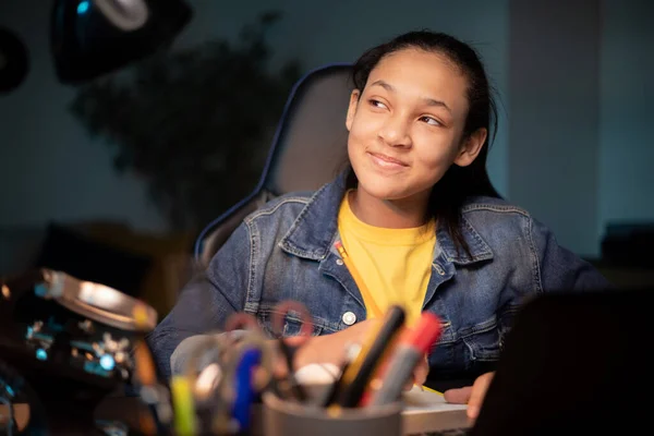 Okula dönelim. Düşünen bir çocuk odadaki bir masada oturur. Ev ödevi yapan kız, online eğitim, tatiller hakkında düşünceli..