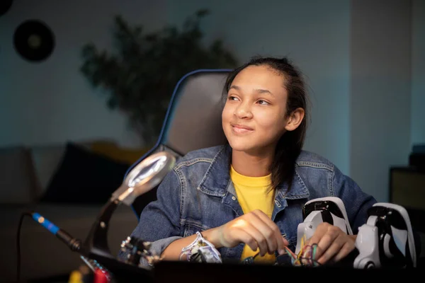 Una chica de ensueño piensa en un concepto para crear un proyecto escolar, un adolescente prepara un robot eléctrico, una robótica apasionada, electrónica Imagen De Stock