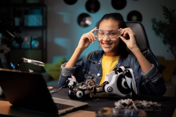 Een tiener maakt zich klaar om een speeltje te maken. Ze doet beschermende brillen om te solderen. Meisje repareert gebroken robot, tweaks afstandsbediening elektronica Rechtenvrije Stockafbeeldingen