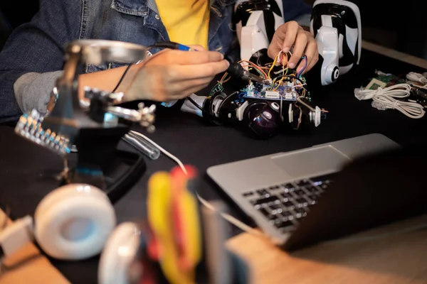 Bureau met laptop, gereedschap, soldeerapparatuur. Jongen repareert robot, soldeert kabels, speelt met elektronica, bouwt speelgoed. Stockfoto