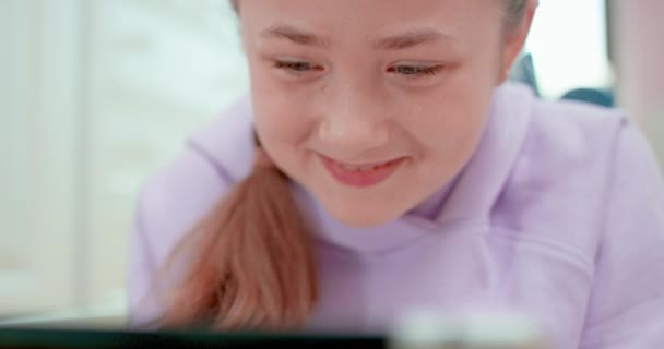 Teenie-Mädchen lacht, wenn sie auf das Tablet schaut. — Stockvideo