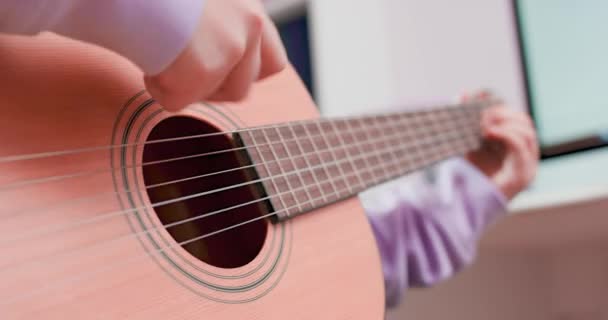 Teen ragazza sta suonando la chitarra e cantando, seduta sul pavimento di fronte alla — Video Stock